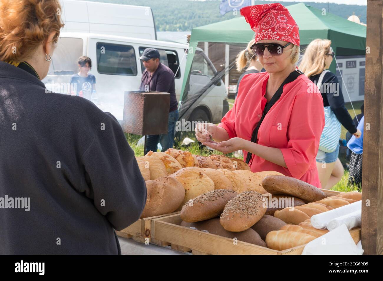 A woman sells baked goods from a tray at the fair of the Karatag music festival. Krasnoyarsk region. Russia. Stock Photo