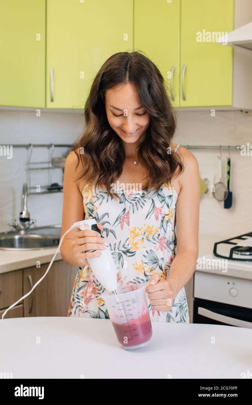 Smiling woman mixing icing with a hand blender Stock Photo