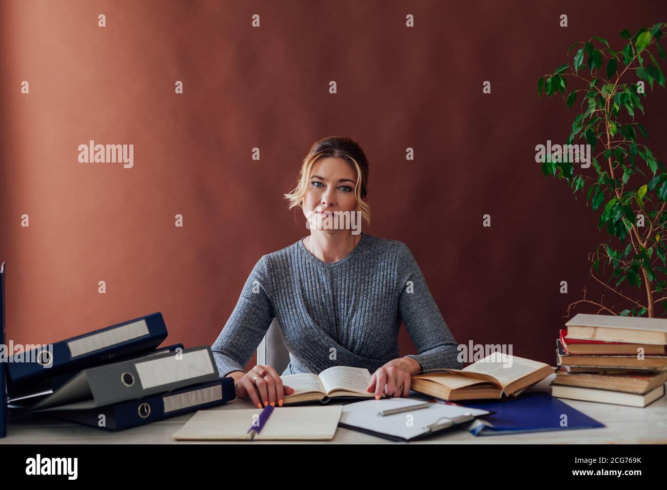 woman in business suit at work in office at a table with books and documents Stock Photo