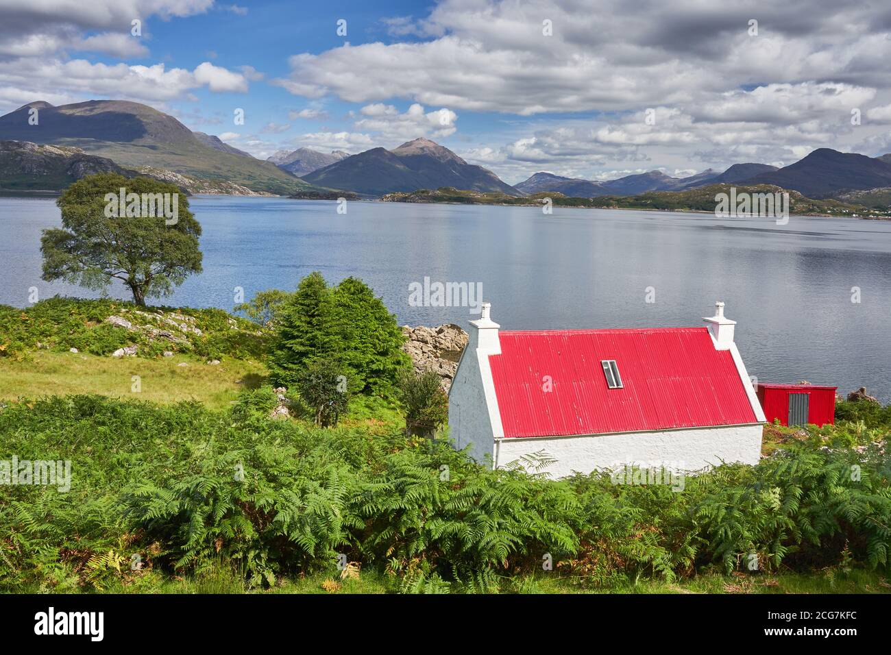Red roofed house near Ardheslaig on shores of Loch Shieldaig Applecross Peninsula Wester Ross Scotland Stock Photo