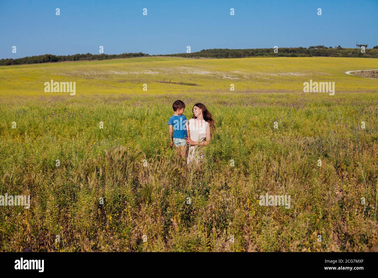 mom and son together in a field with yellow flowers Stock Photo - Alamy