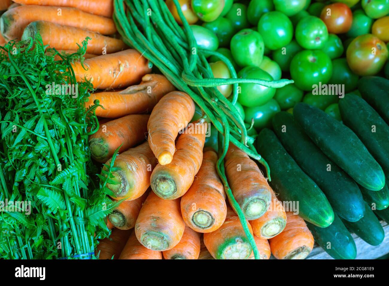 Ripe vegetable on market. Carrot, cucumber and bean pile closeup photo. Green and red vegetable on organic farmer market. Autumn seasonal harvest fest Stock Photo