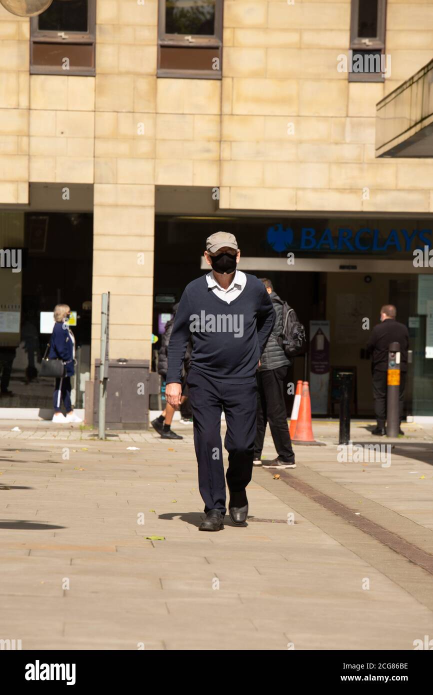 Bolton City Centre during new lockdown rules, man walks down street wearing face mask in Bolton City Centre Stock Photo
