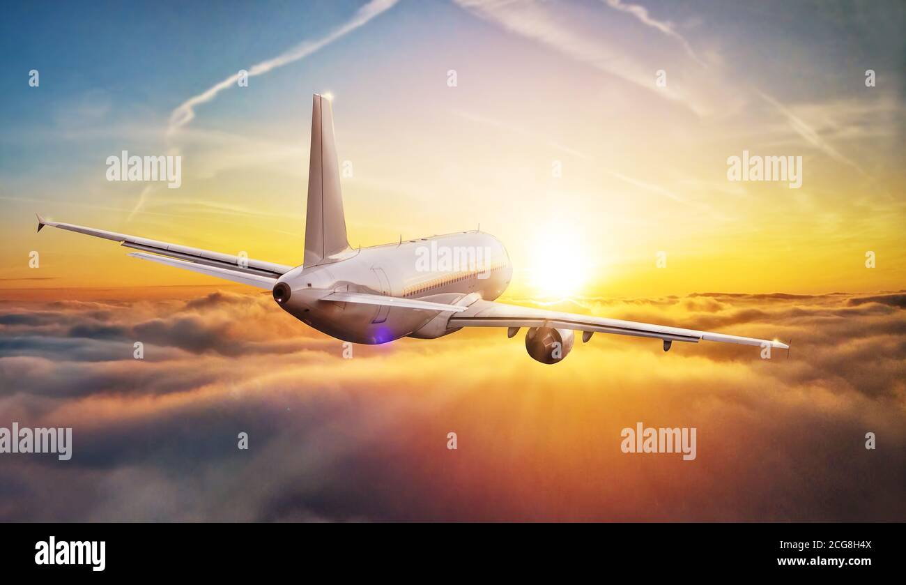 Commercial airplane flying above clouds in dramatic sunset light. High ...