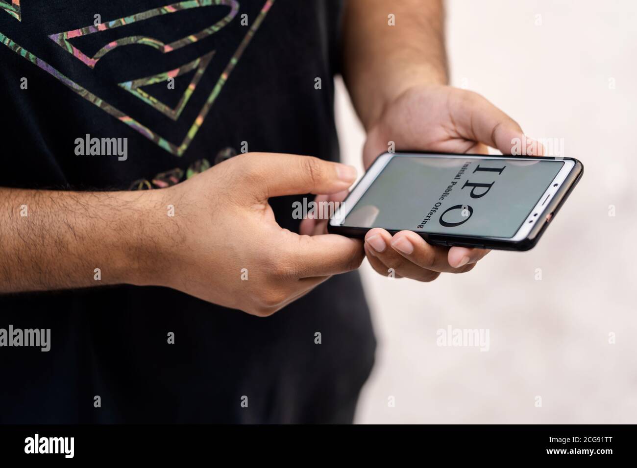 IPO concept. Indian working man hand holding smart phone & showing Initial Public Offering which is displayed on it's screen isolated on white backgro Stock Photo