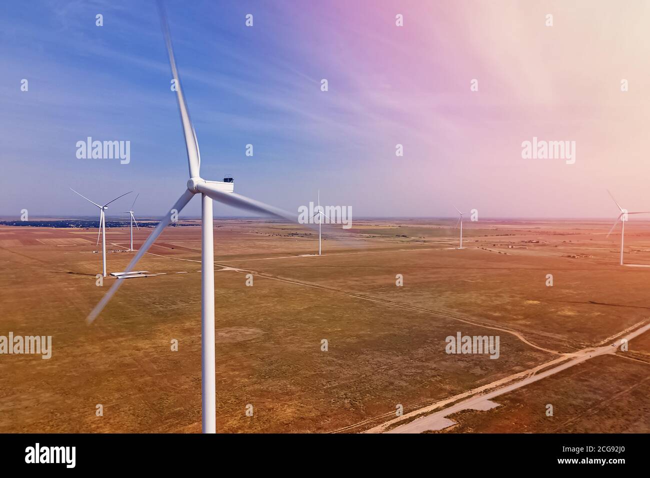 Wind turbines producing alternative green energy against the blue sky Stock Photo