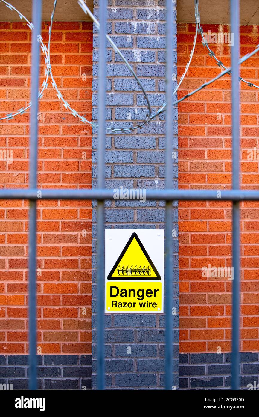 Yellow Razor wire sign on outside wall Stock Photo
