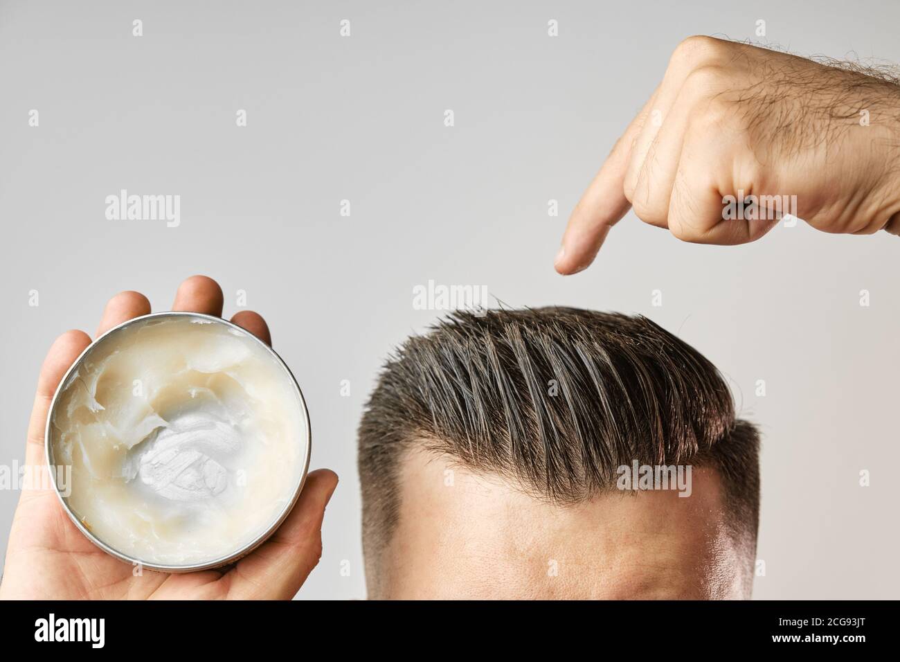Man applying a clay, pomade, wax, gel or mousse from round metal box for  styling his hair after barbershop hair cut. Advertising concept of mans  Stock Photo - Alamy