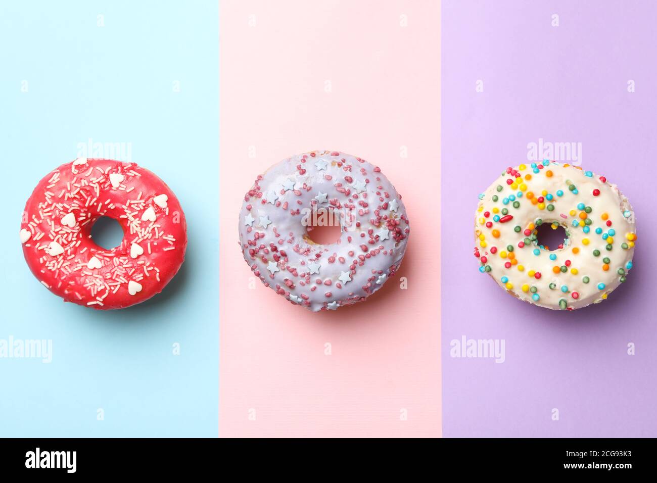 Tasty donuts on three tone background, top view Stock Photo
