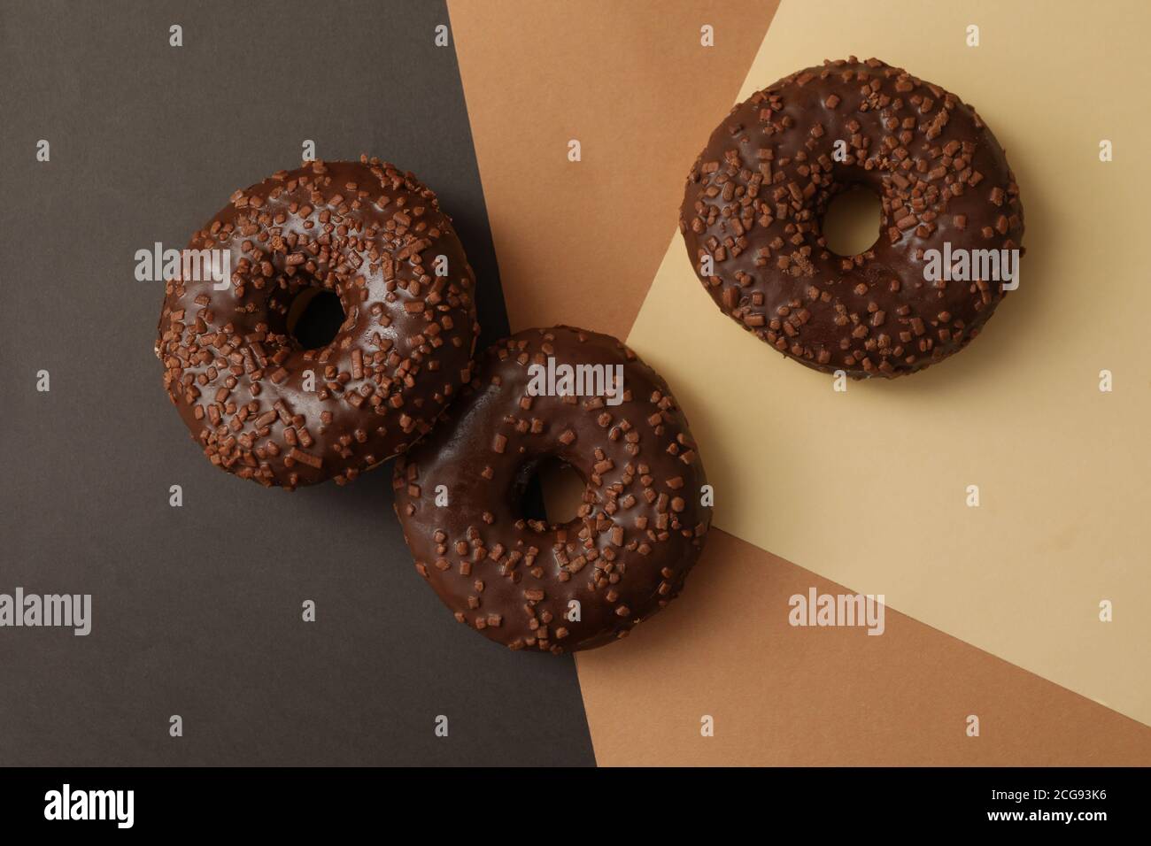 Tasty chocolate donuts on three tone background Stock Photo