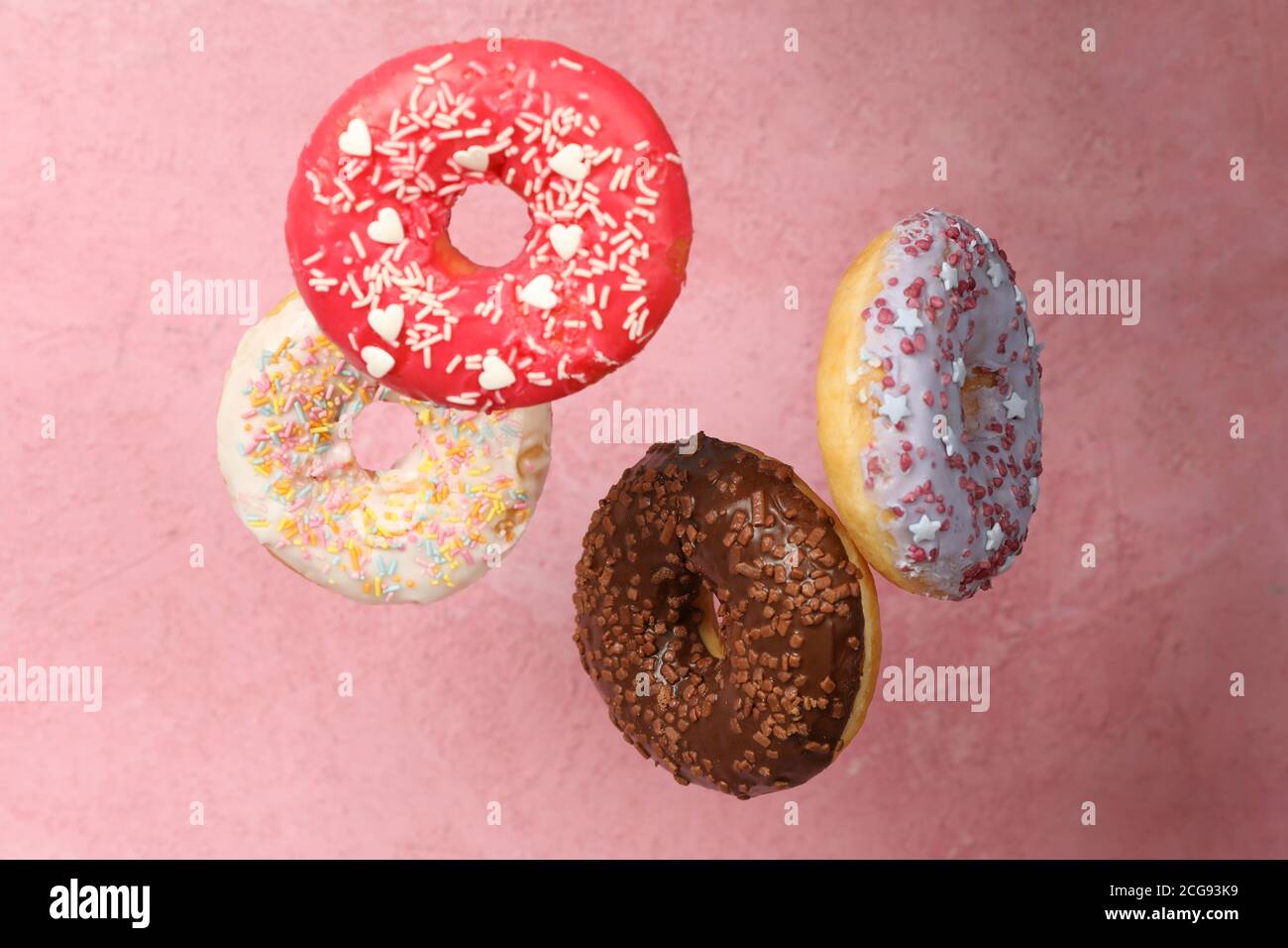 Four different tasty donuts on pink background Stock Photo