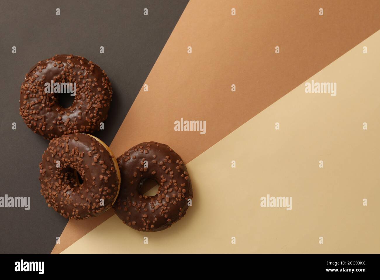 Tasty chocolate donuts on three tone background Stock Photo