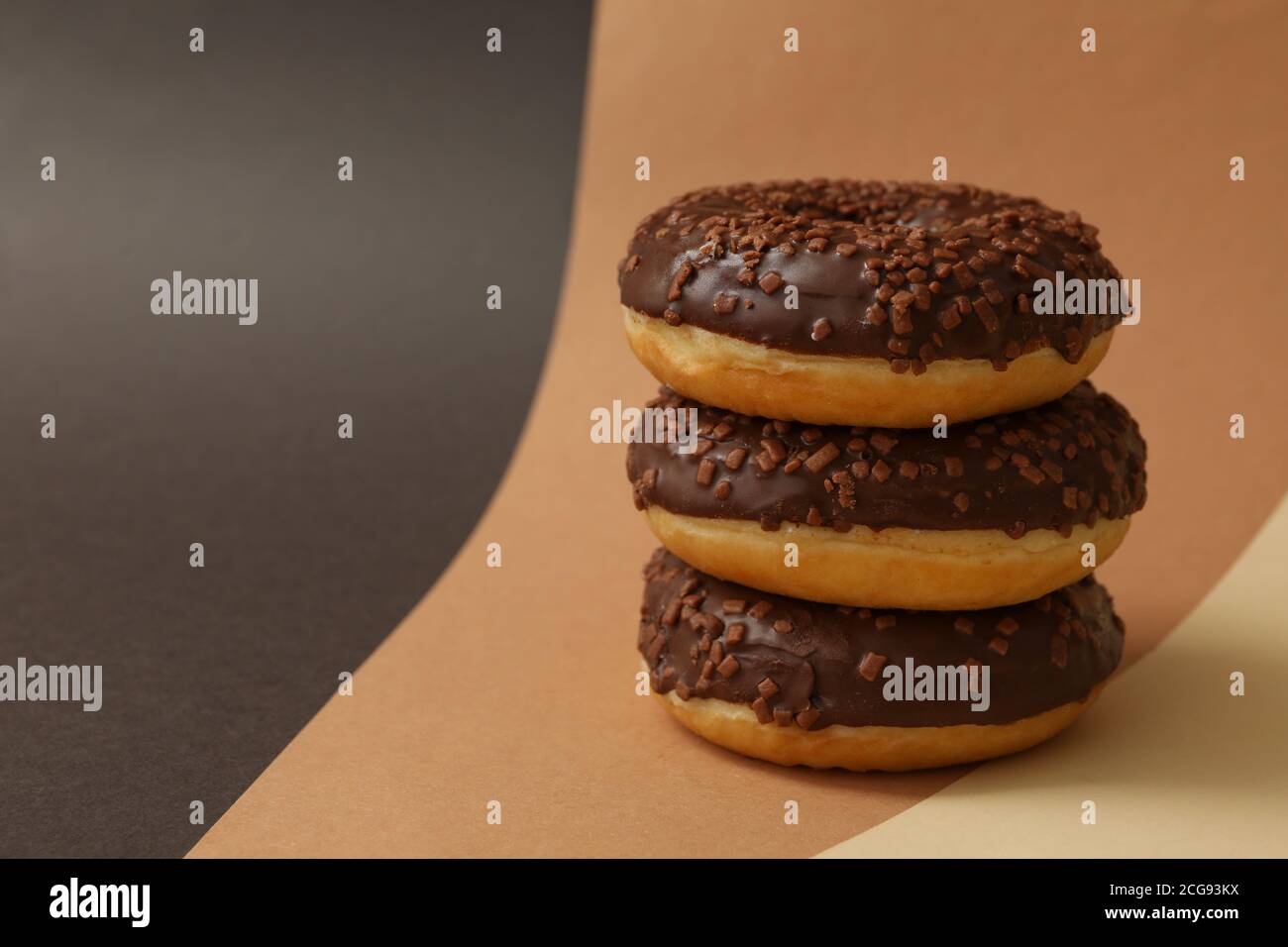Tasty chocolate donuts on three tone background Stock Photo