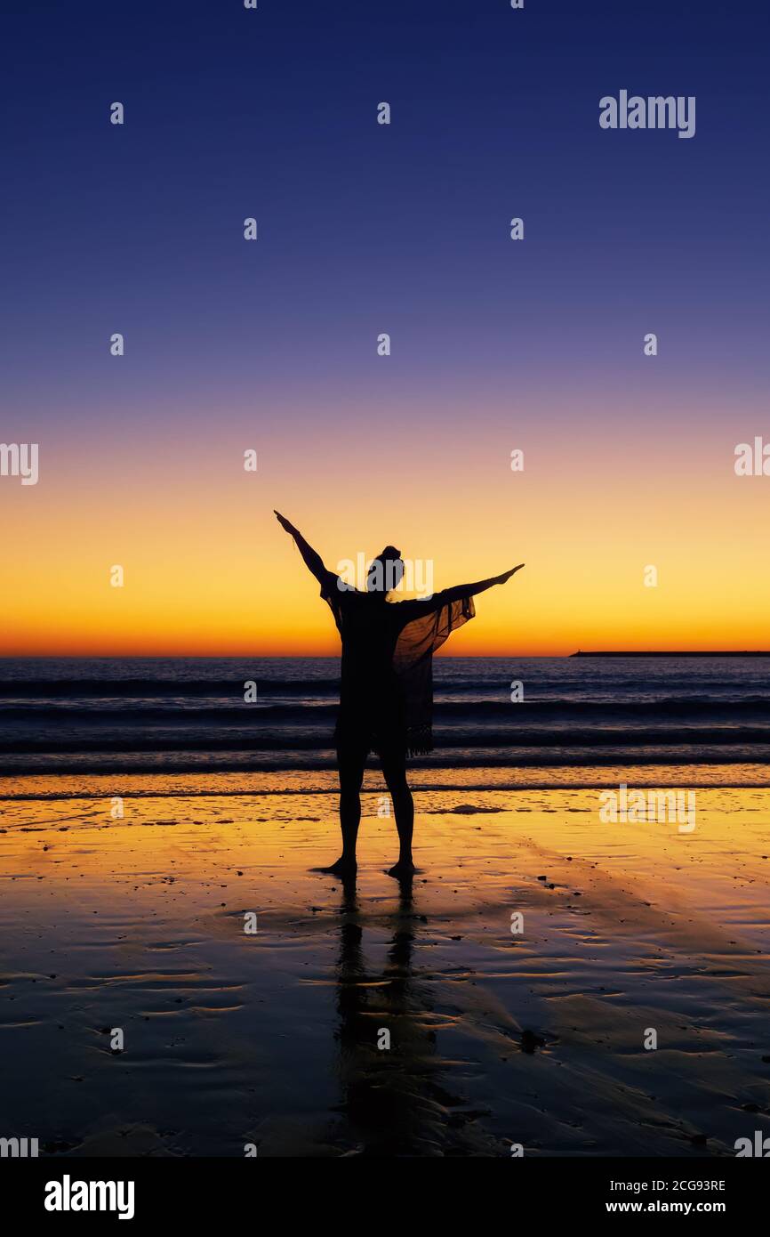 Woman in the beach with arms open and raised Stock Photo