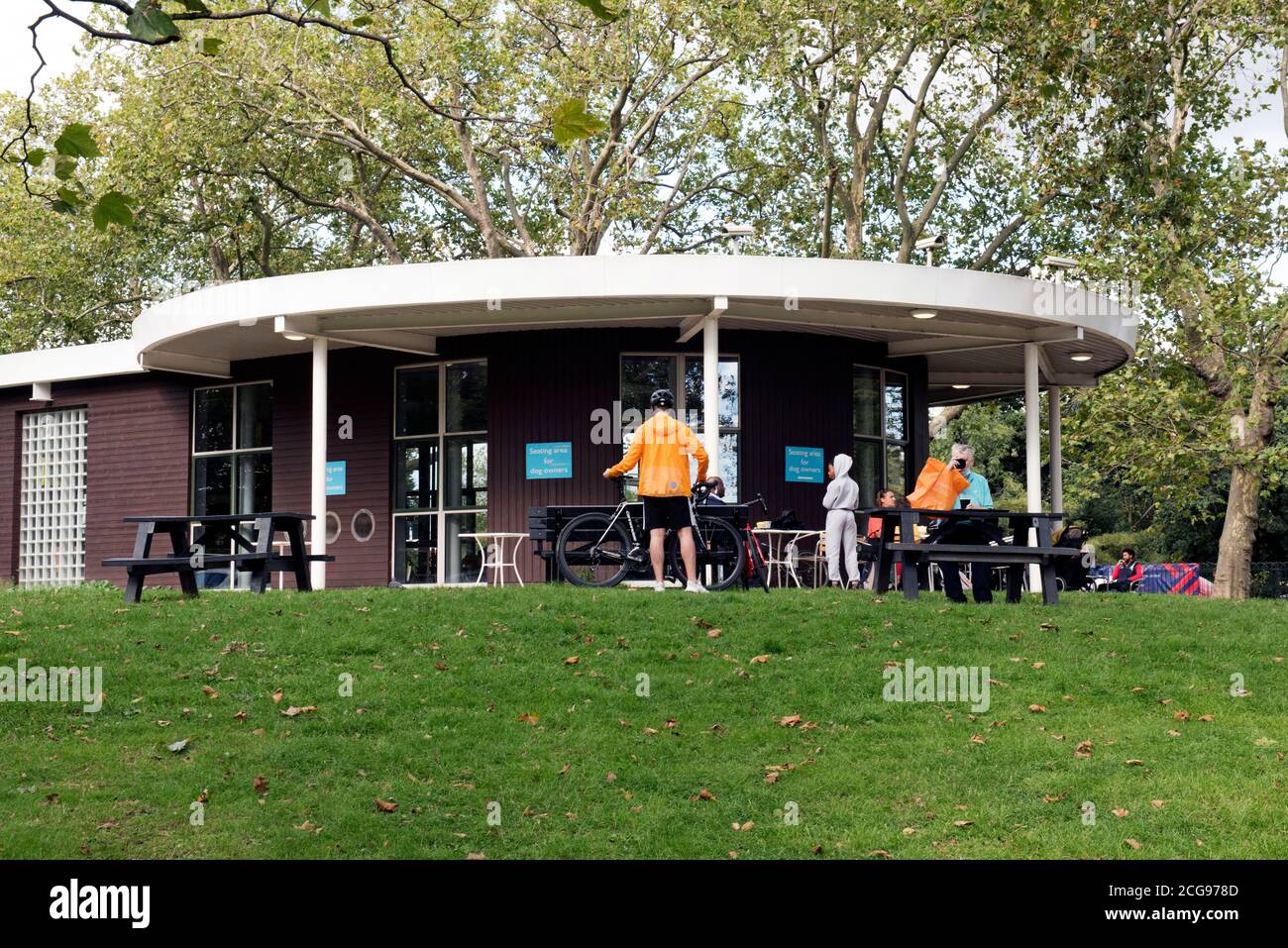 Café Finsbury Park with cyclist in orange jacket in front, London Borough of Harringey Stock Photo