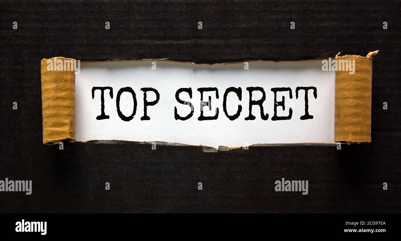 The word 'top secret' appearing behind torn black paper. Business concept. Stock Photo