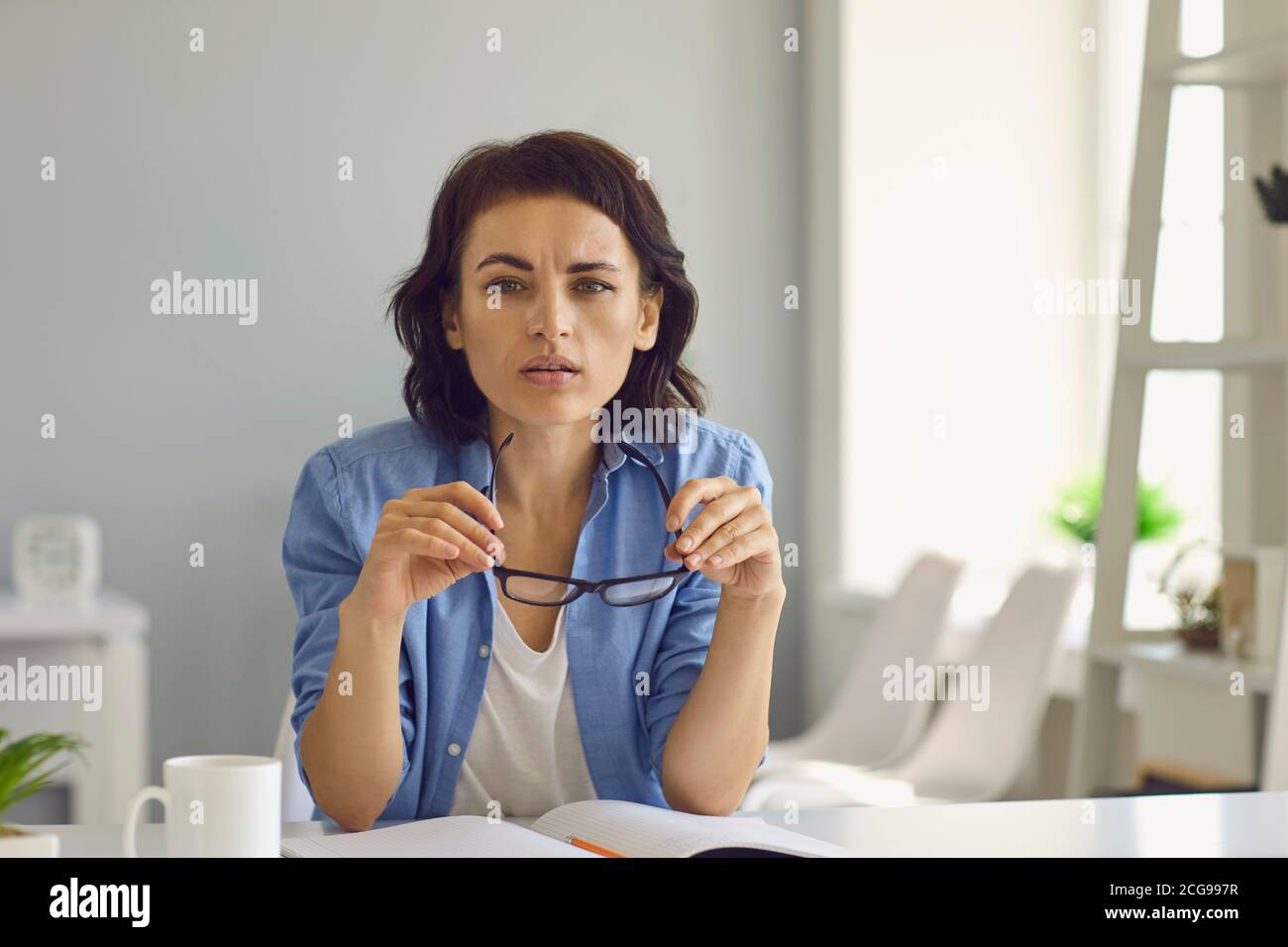 Young attentive woman looking at web camera during online meeting Stock Photo