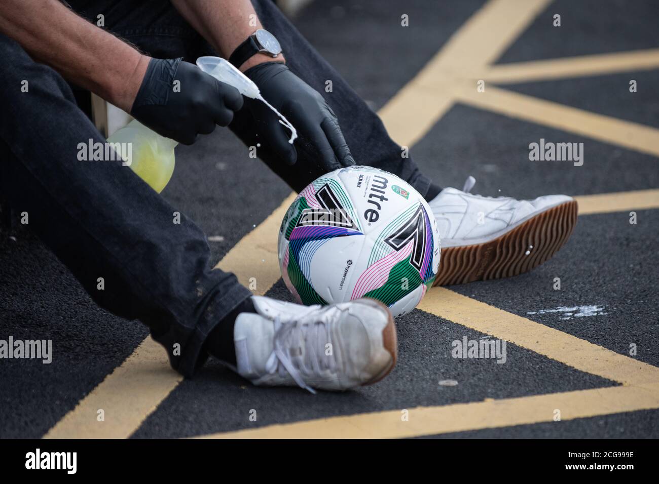 Steward sanitising football during coronavirus pandemic 2020. Stock Photo