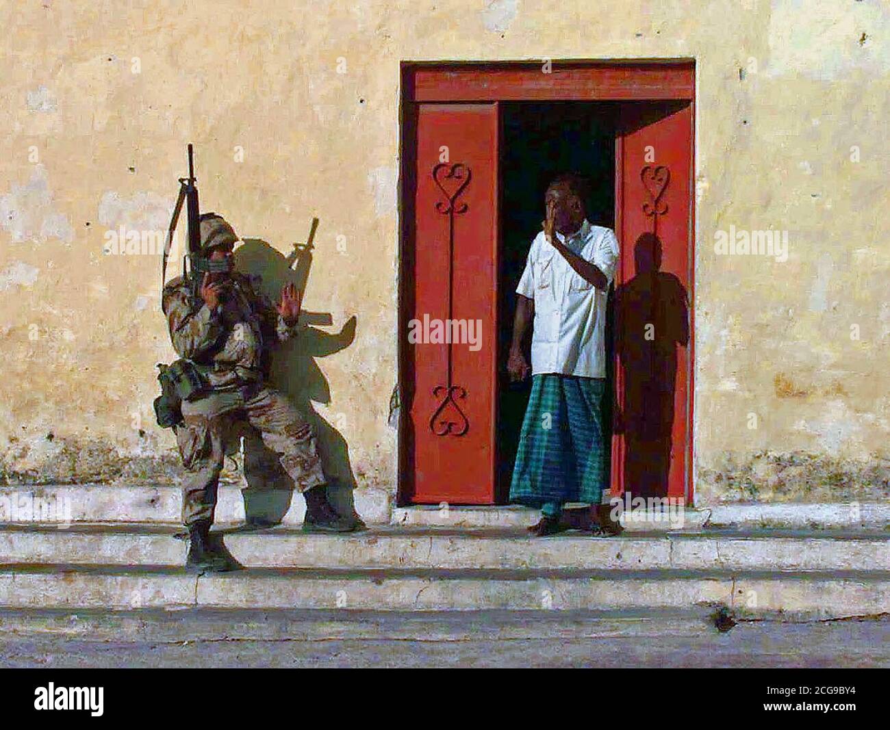 1992 - A US Marine and a Somali nervously greet each other as the man comes out of his house to see what the Marines are doing.  RESTORE HOPE Stock Photo