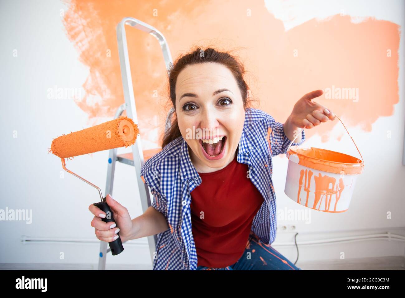 Image showcasing Funny smiling woman painting interior wall of new house. Redecoration ...