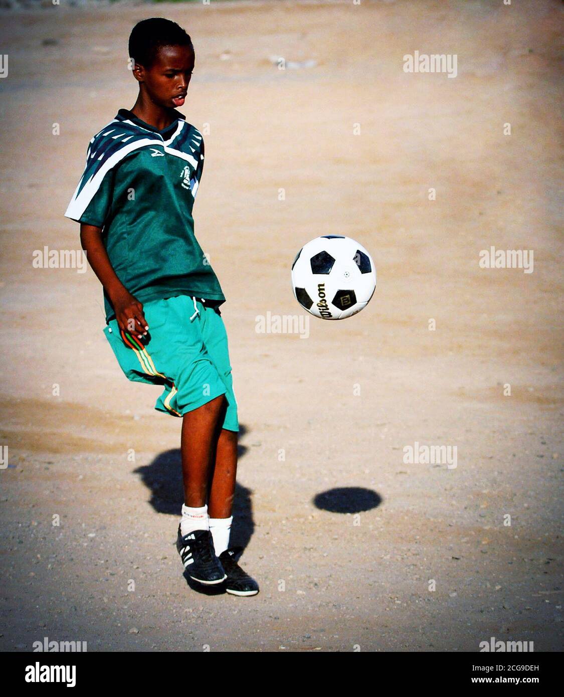 A boy from the Djibouti City's Boy's Orphanage kicks a soccer ball donated by U.S. Military Service Members deployed with Combined Joint Task Force - Horn of Africa (CJTF-HOA).  - Horn of Africa is a unit of U.S. Central Command that conducts operations and training to assist Partner nations to combat terrorism in order to establish a secure environment and enable regional stability. Stock Photo