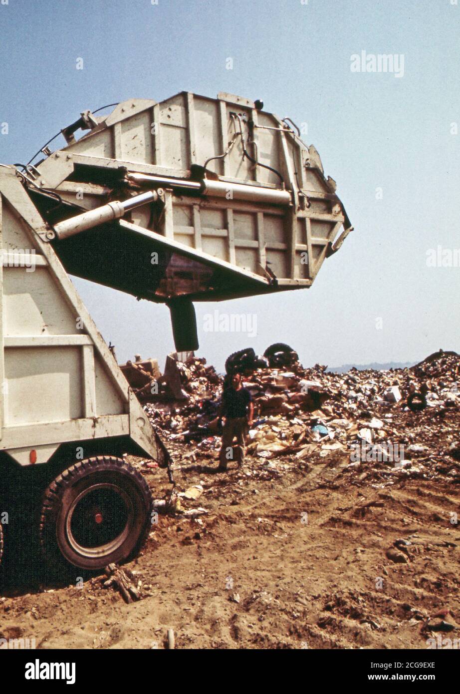 1970s photo of garbage truck dumping garbage in the city dump Stock