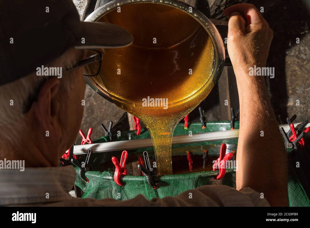 The beekeeper filters the remaining wax from the honey before packing it. Stock Photo