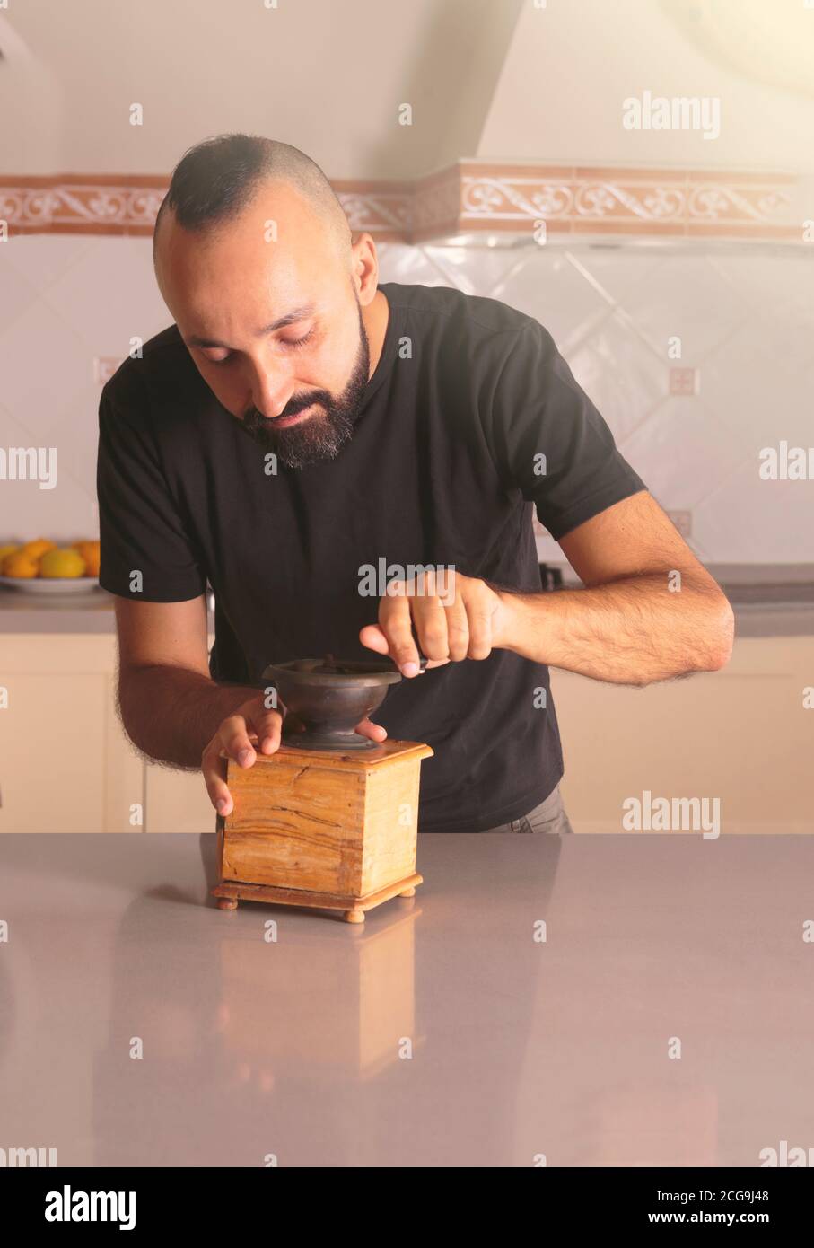 Happy young hispanic man using a classic coffee grinder Stock Photo