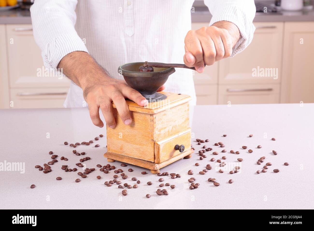Caucasian man in white clothes grinding coffee Stock Photo
