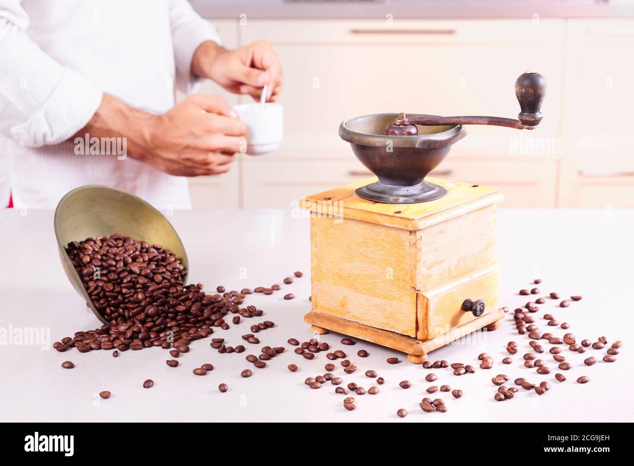 Antique coffee grinder, a bowl with beans spilt and a man with a cup of coffee Stock Photo