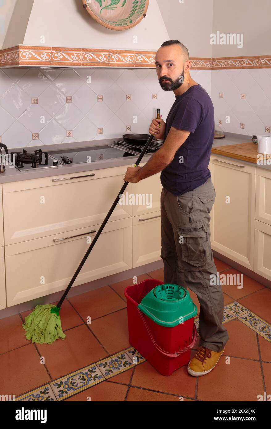 Young hispanic self-sufficient man mopping the floor Stock Photo