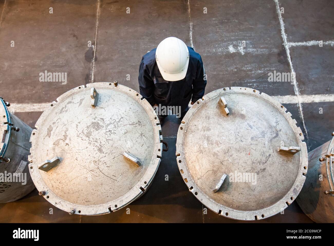 Titanium metallurgy plant. Metal storage tank for titanium metal rods. Engineer in white hardhat. Stock Photo