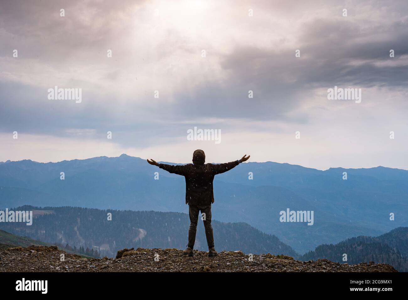 Landscape with silhouette of a standing happy man and raised-up arms on ...