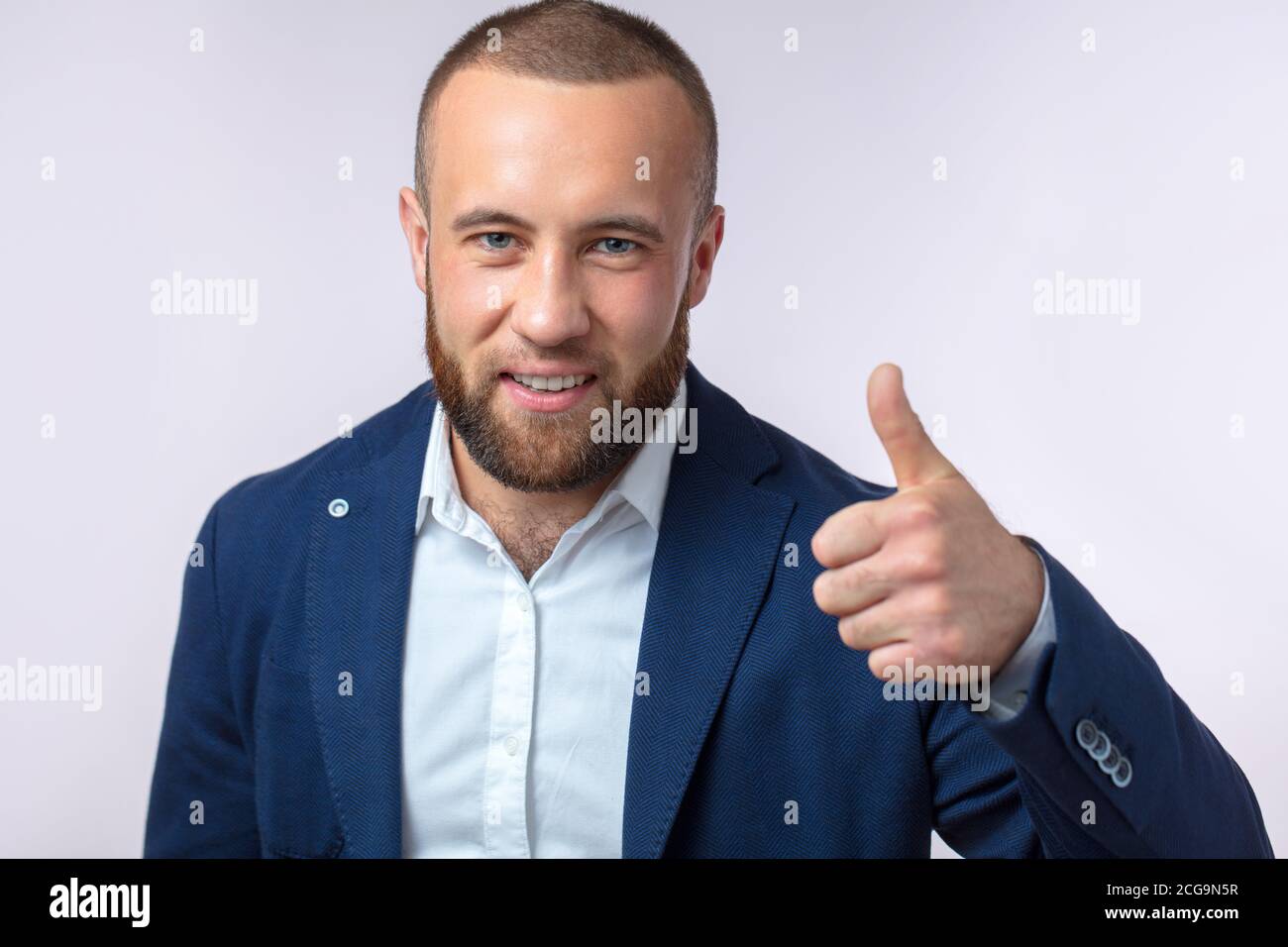 Handsome Chief Executive in formal wear gesturing that you have made a right choice by thumbing up at camera. Isolated over studio white background wi Stock Photo