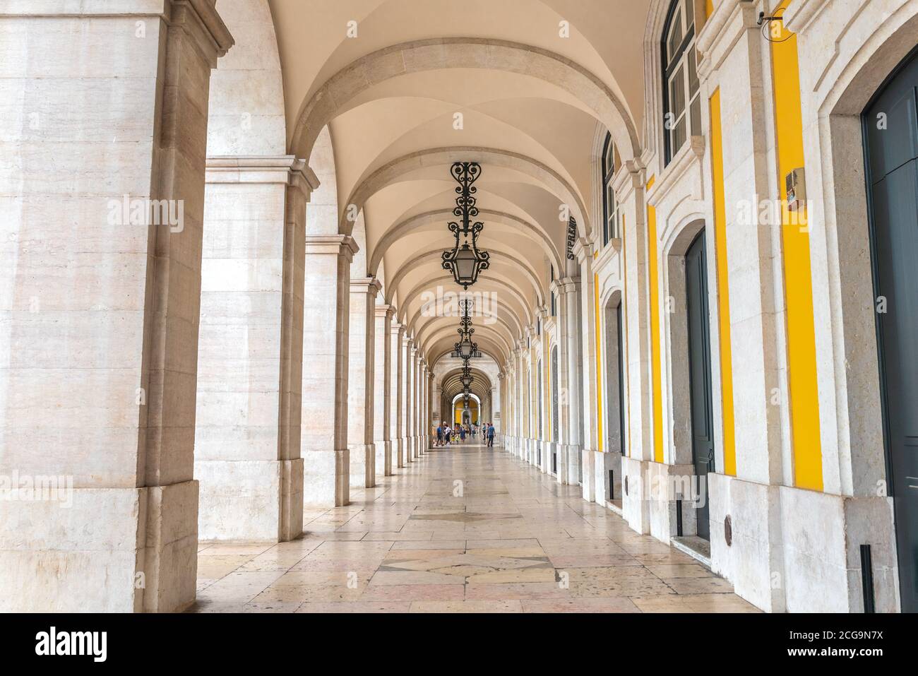 Marble arcade with beautiful lamps, yellow painting and architectural details in Praca do Comercio, Lisbon - Portugal Stock Photo