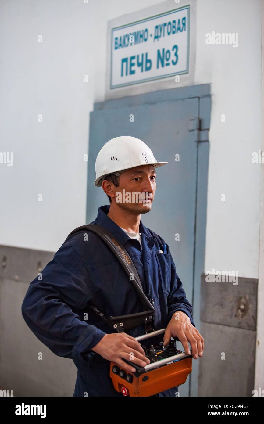 Asian worker using crane on titanium metallurgy plant. For loading titanium sponge to vacuum arc furnace. Stock Photo