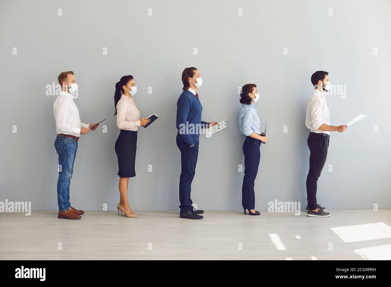 Job seekers wearing face masks standing in row keeping safe distance