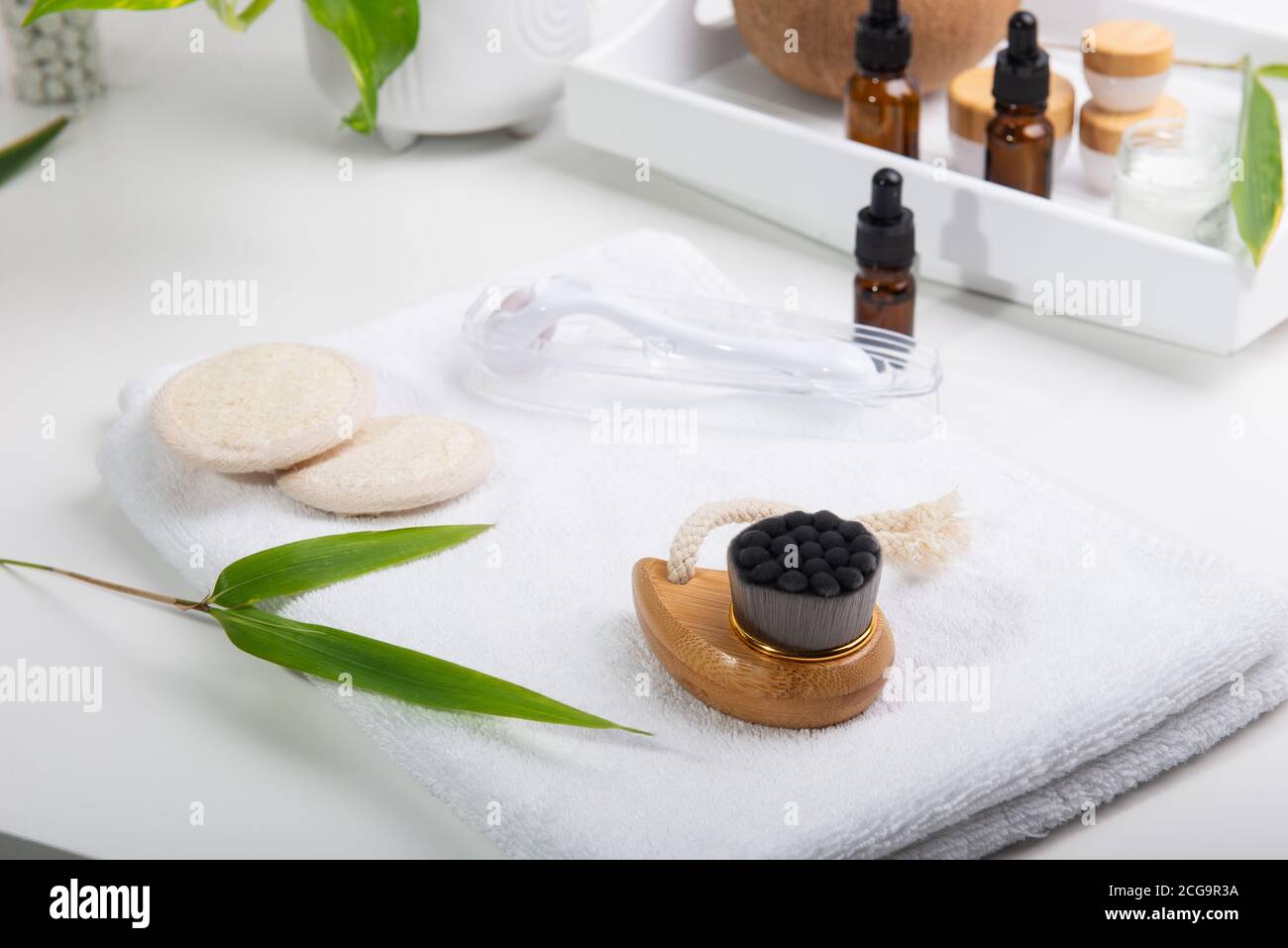 Home self care for face massage. Dry lymphatic drainage massage wooden brushe, derma mezoroller and loofah pads for skin care on a white tray. Bathroo Stock Photo
