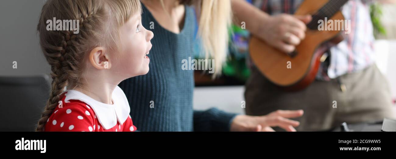 Parents teach daughter to play musical instruments Stock Photo