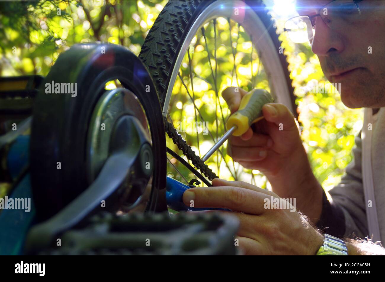 Taking care of the bike outdoors. Repair of the chain on a sprocket on a bicycle. Stock Photo