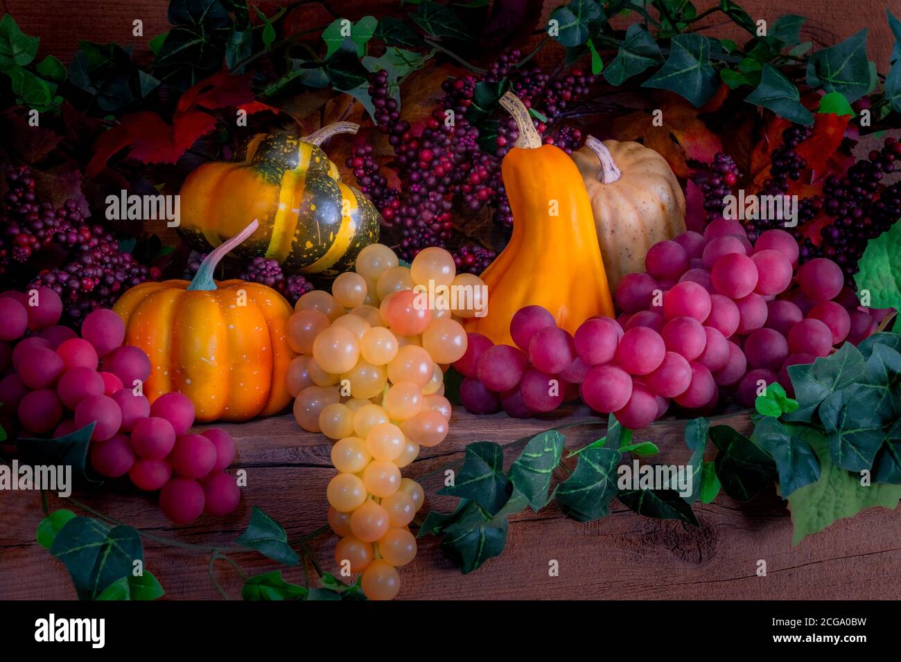 A rustic wood mantel is decorated with berries, grapes, pumpkins and gourds for the autumn celebrations. Stock Photo