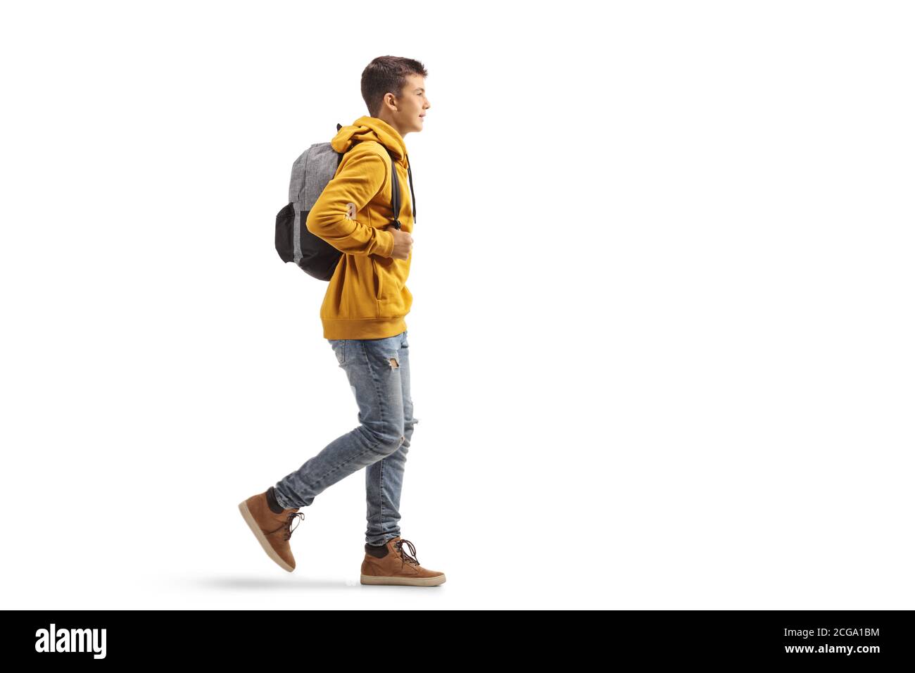 Full length profile shot of a male teenage student in a yellow hoodie walking isolated on white background Stock Photo