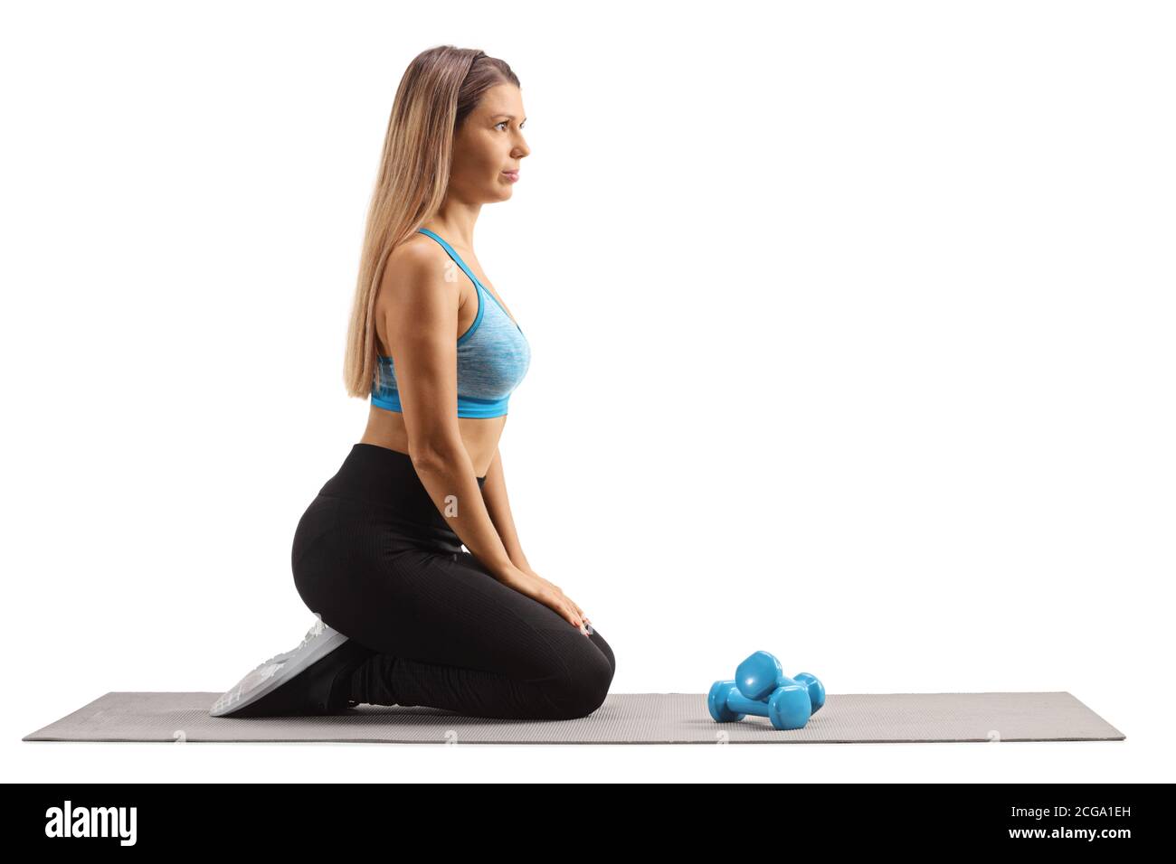 Young woman kneeling on an exercise mat and preparing to exercise with