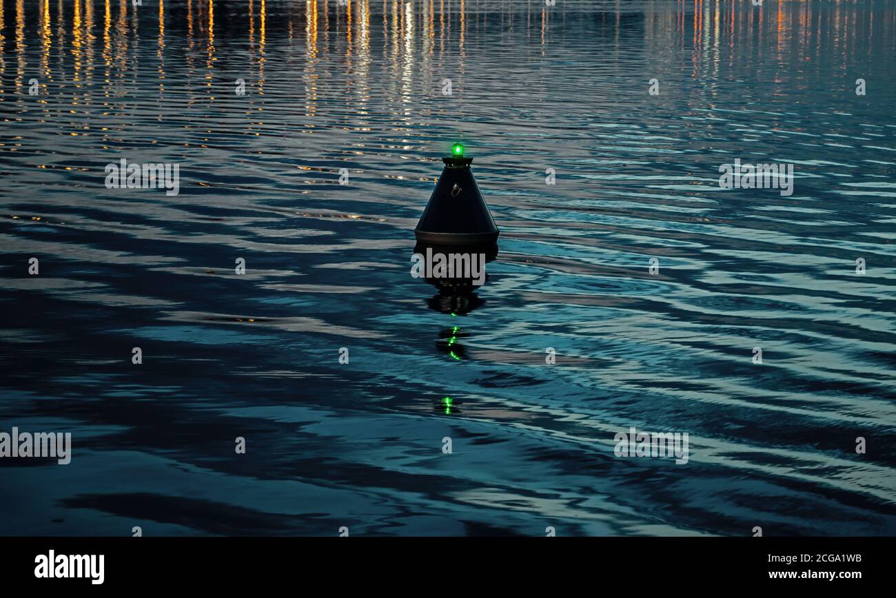 View of the blue dark waters of the river and the buoy, which sways on the waves. buoy sways in twater as safety warning and navigation marker at harbor or port Stock Photo