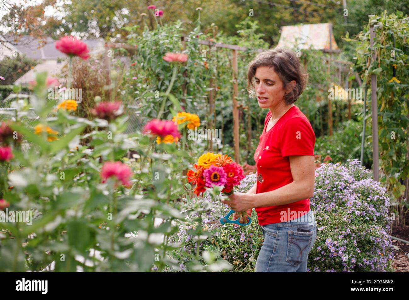 A woman stands in a beautiful flower-filled garden holding a bouquet ...