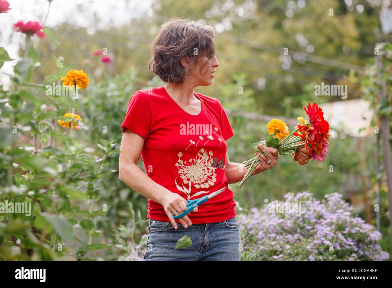 A woman stands with a bouquet of wildflowers in a beautiful garden ...