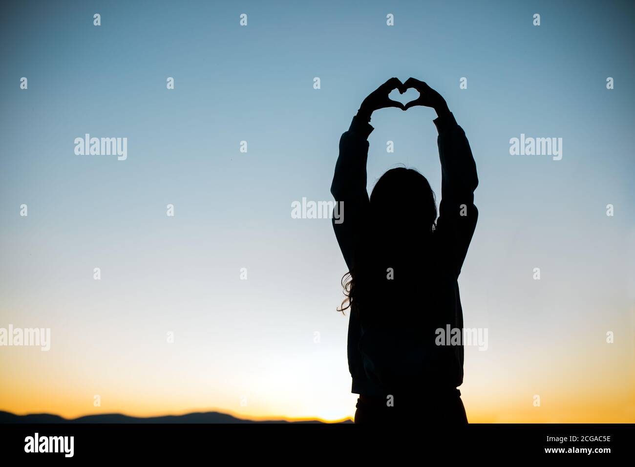 Hands form a Heart for Love Silhouette with Sunset or Sunrise Stock Photo