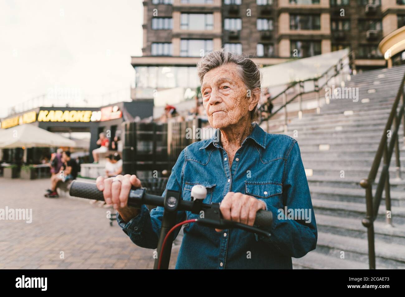 Cheerful elderly woman on a scooter. Grandma rides a scooter. Grandmother using urban personal