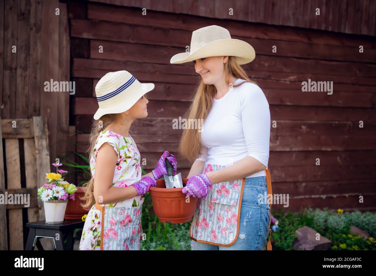 Woman And Girl Mother And Daughter Gardening Together Planting Flowers In The Garden Stock 