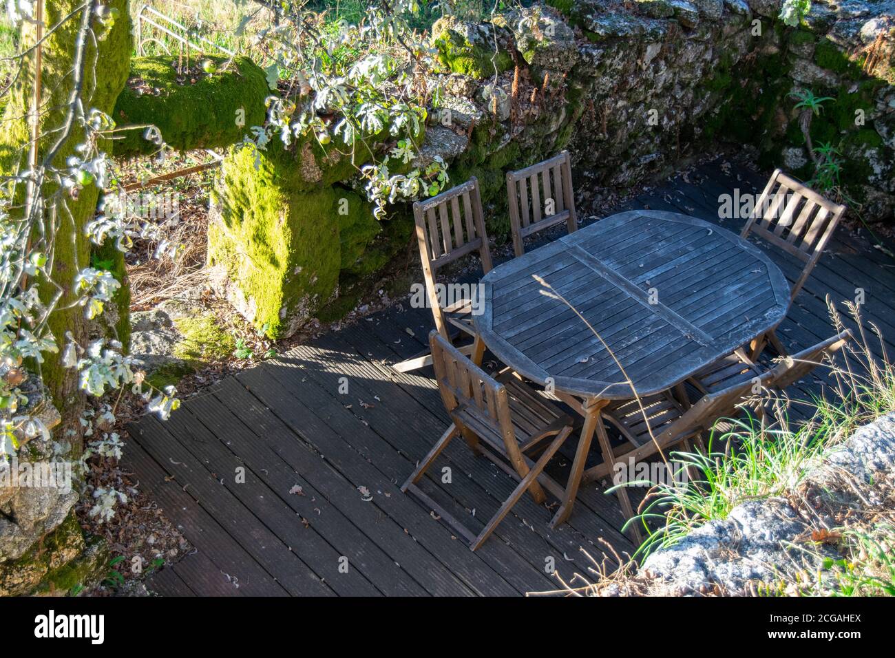 Vintage family empty table reunion place on wood deck in old stone house remains. Empty seats, old times reunions. Table reunion conversations. Stock Photo
